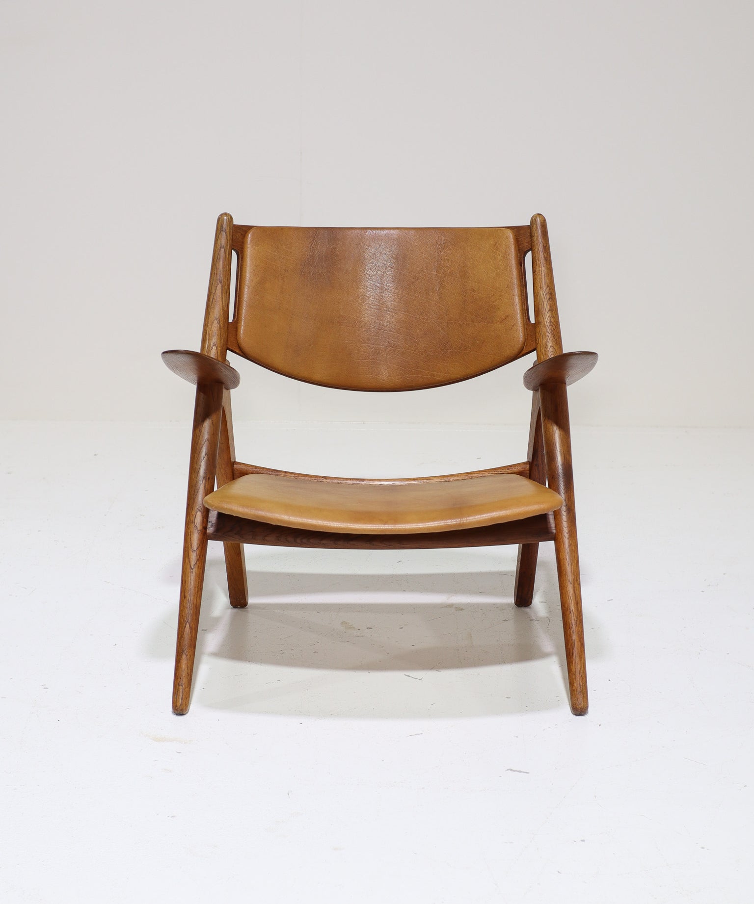 Hans_J._Wegner_CH28_“Sawbuck”_Armchair_in_Oak_and_Cognac_Leather,_1950s