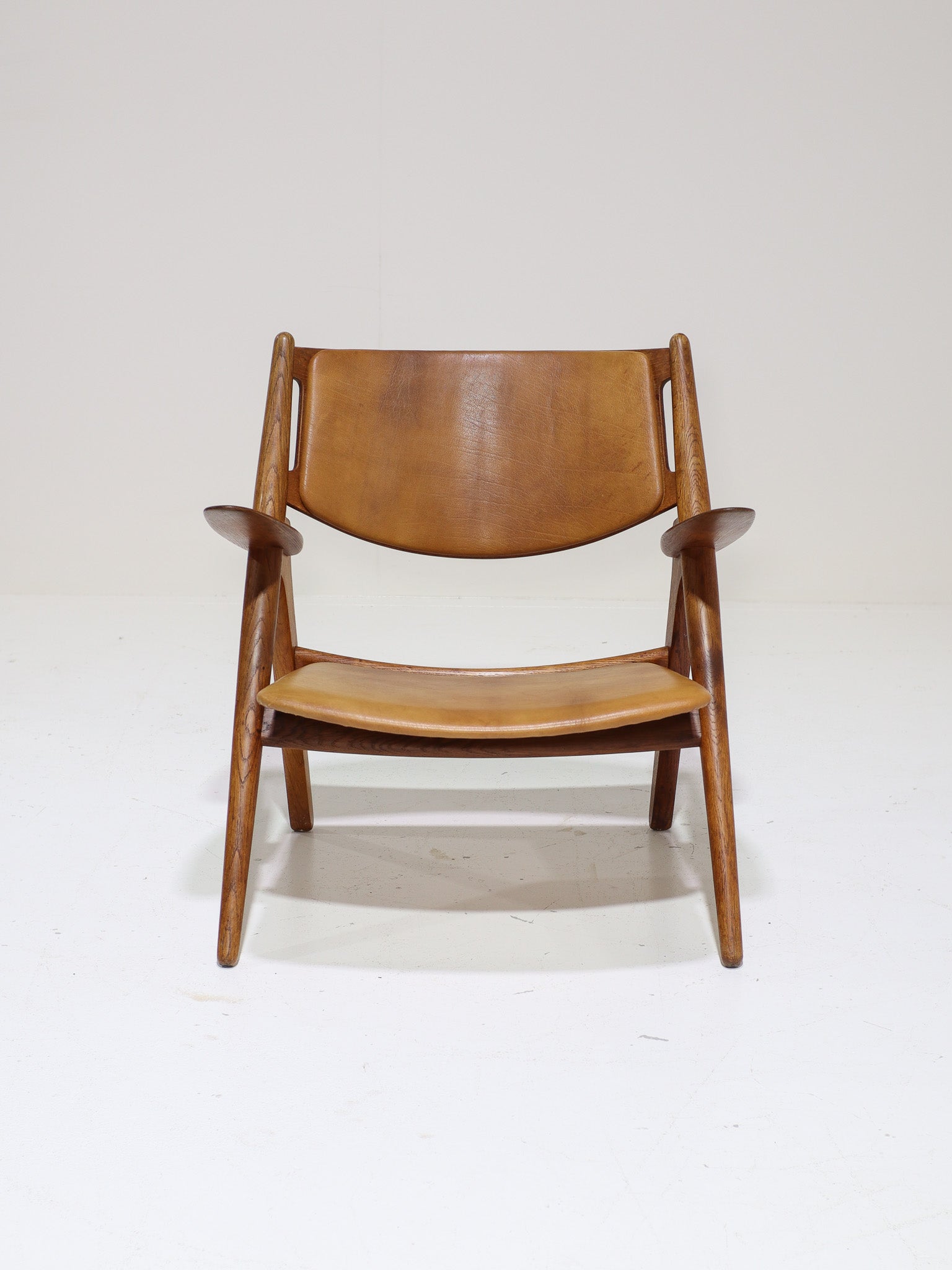 Hans_J._Wegner_CH28_“Sawbuck”_Armchair_in_Oak_and_Cognac_Leather,_1950s