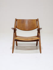 Hans_J._Wegner_CH28_“Sawbuck”_Armchair_in_Oak_and_Cognac_Leather,_1950s