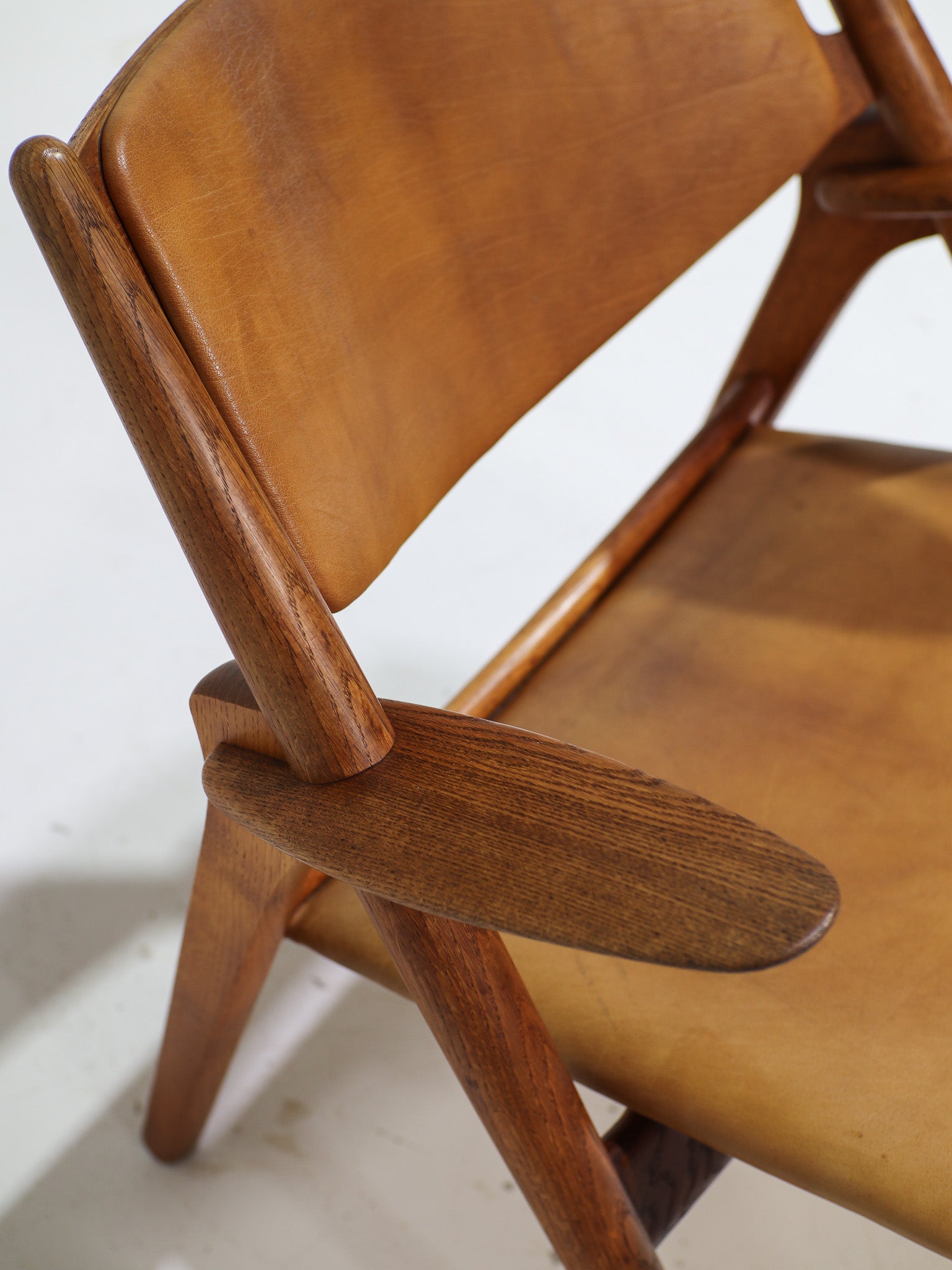 Hans_J._Wegner_CH28_“Sawbuck”_Armchair_in_Oak_and_Cognac_Leather,_1950s