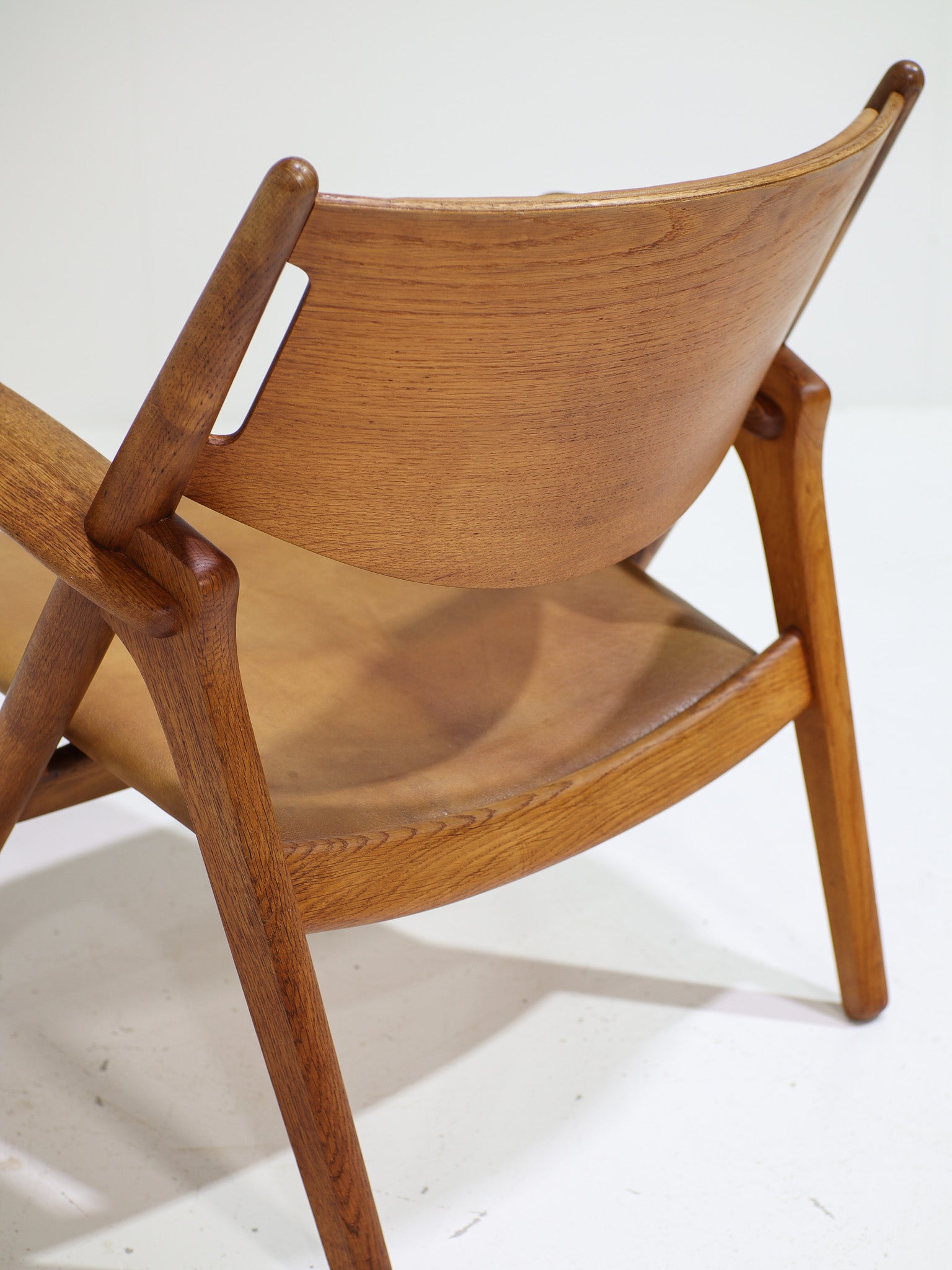 Hans_J._Wegner_CH28_“Sawbuck”_Armchair_in_Oak_and_Cognac_Leather,_1950s