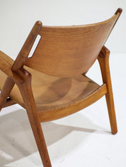 Hans_J._Wegner_CH28_“Sawbuck”_Armchair_in_Oak_and_Cognac_Leather,_1950s