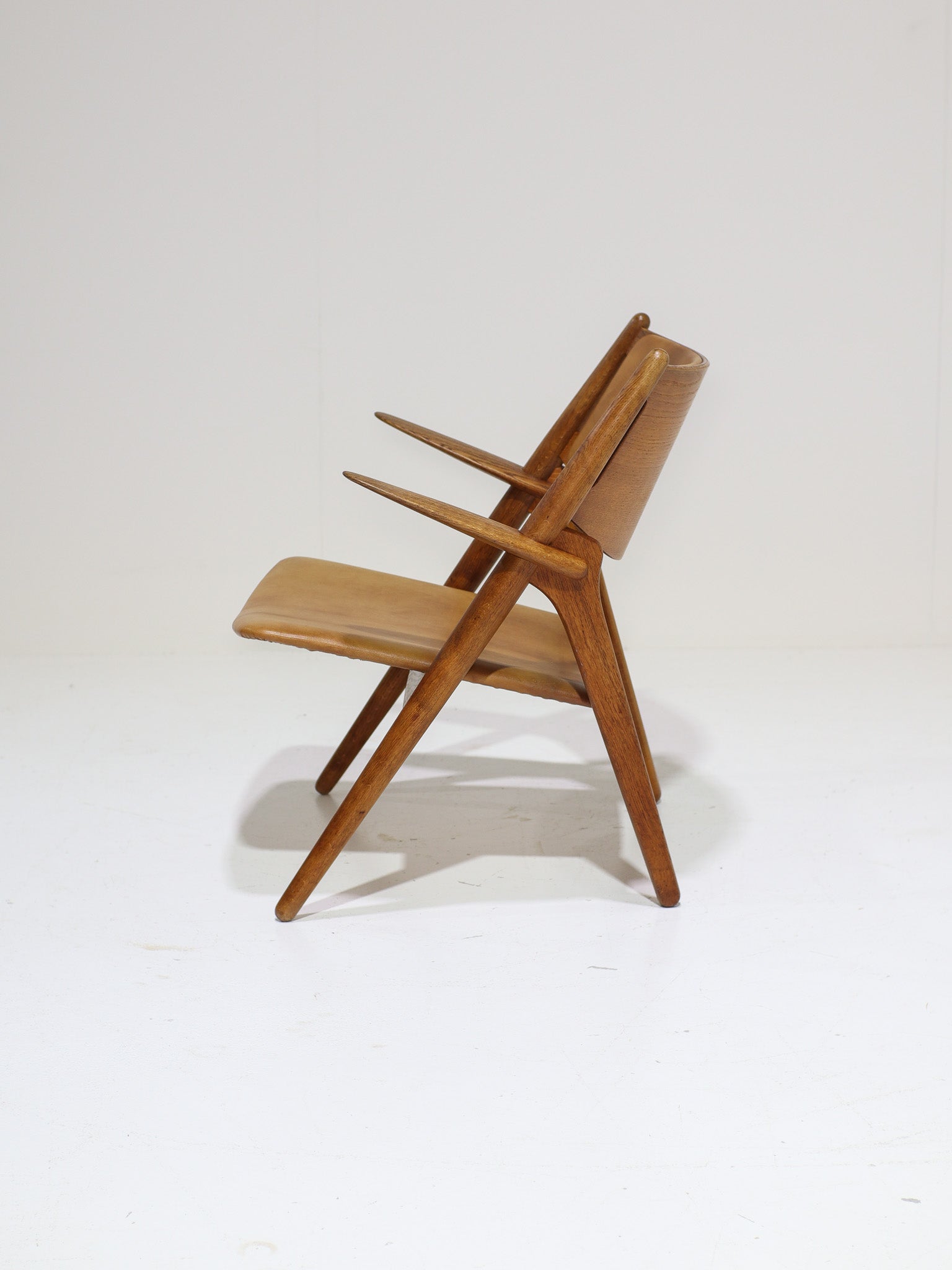 Hans_J._Wegner_CH28_“Sawbuck”_Armchair_in_Oak_and_Cognac_Leather,_1950s