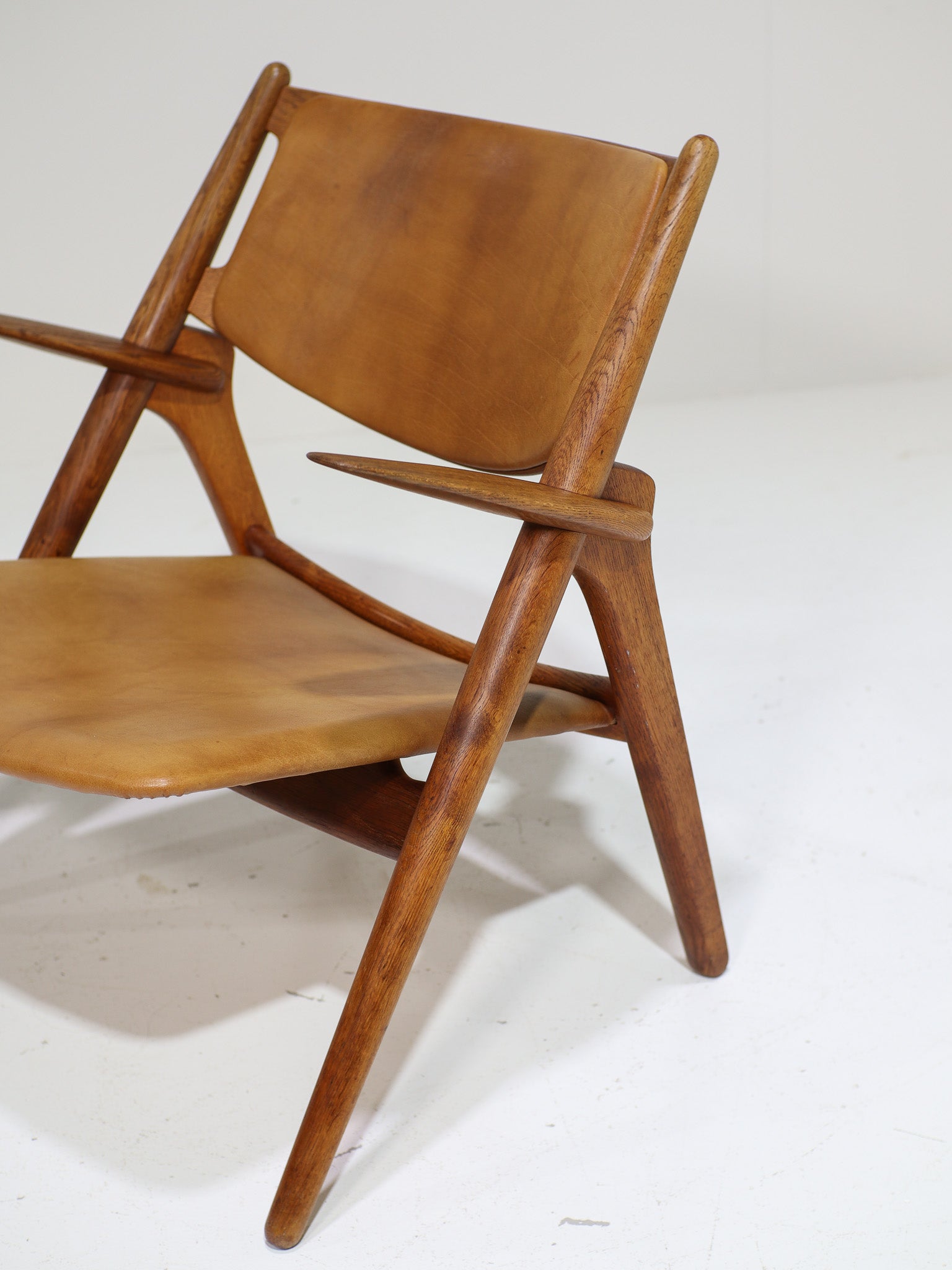 Hans_J._Wegner_CH28_“Sawbuck”_Armchair_in_Oak_and_Cognac_Leather,_1950s